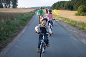 Familie fährt auf Fahrrädern auf einer Straße durch Felder