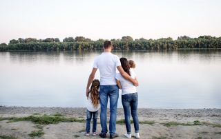 Eine Familie steht am Rheinufer und schaut aufs Wasser