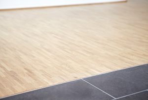 Übergang von hellem Parkett zu dunkler Fliese