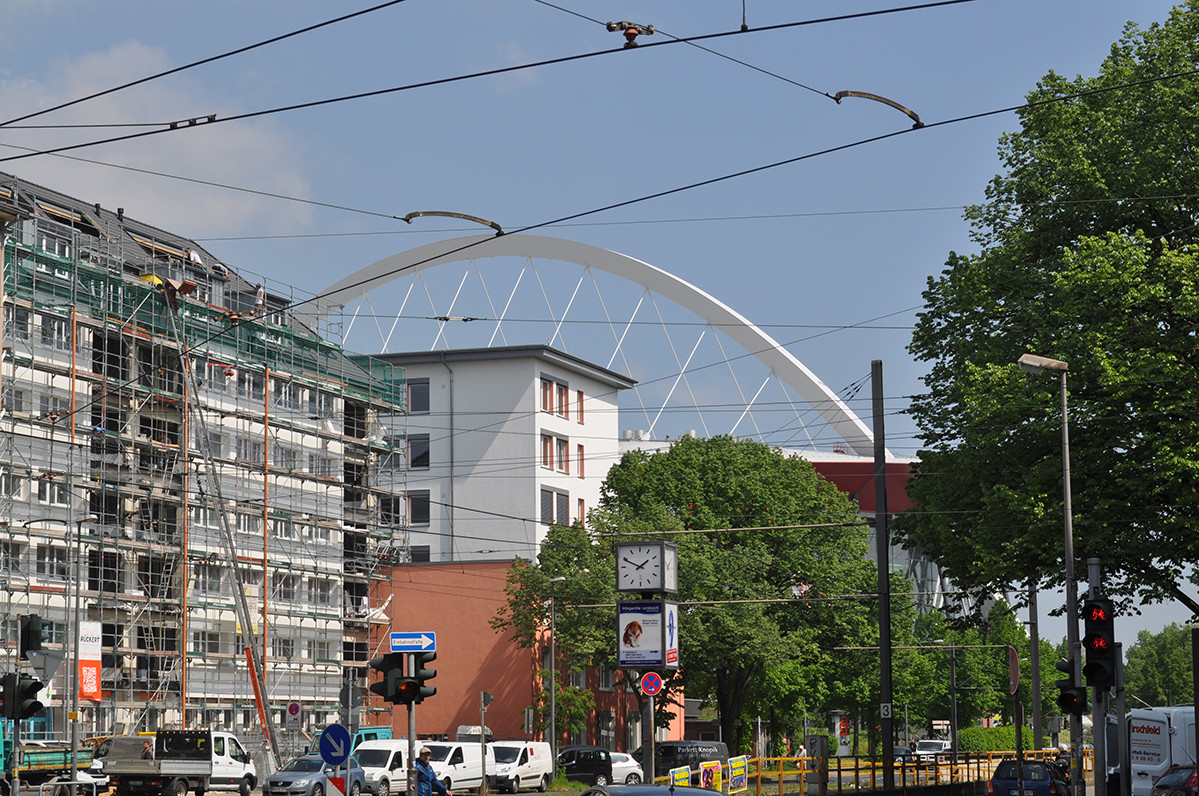 Häuserfassaden mit dem Dach der Lanxess-Arena im Hintergrund