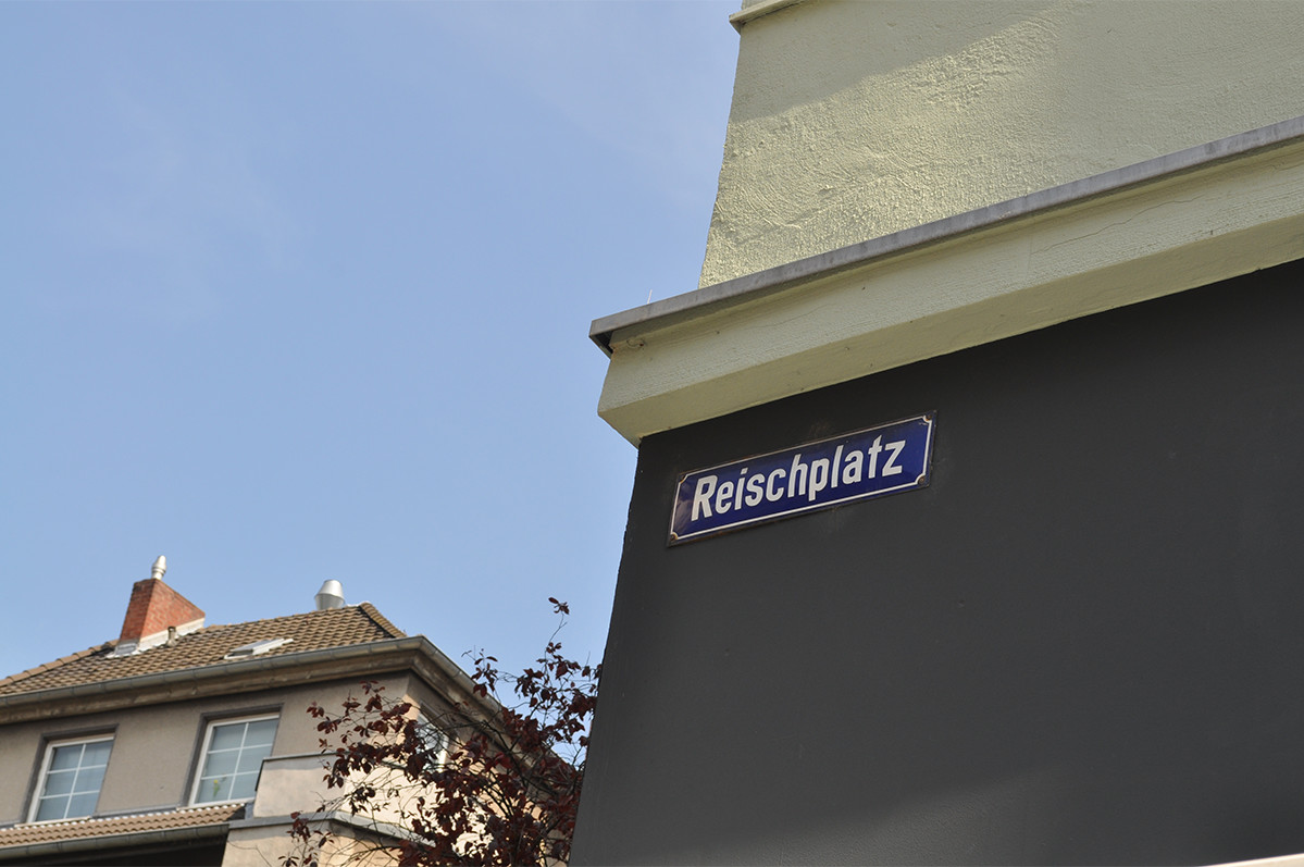 Ecke eines Gebäudes mit Straßenschild "Reischplatz"
