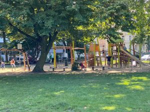 Spielende Kinder auf einem Spielplatz unter Bäumen