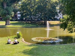 Frei junge Frauen sitzen an einem Teich im Park