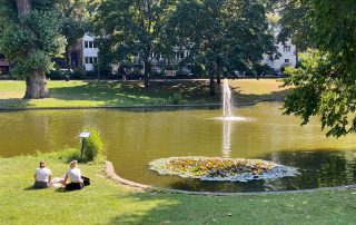Frei junge Frauen sitzen an einem Teich im Park